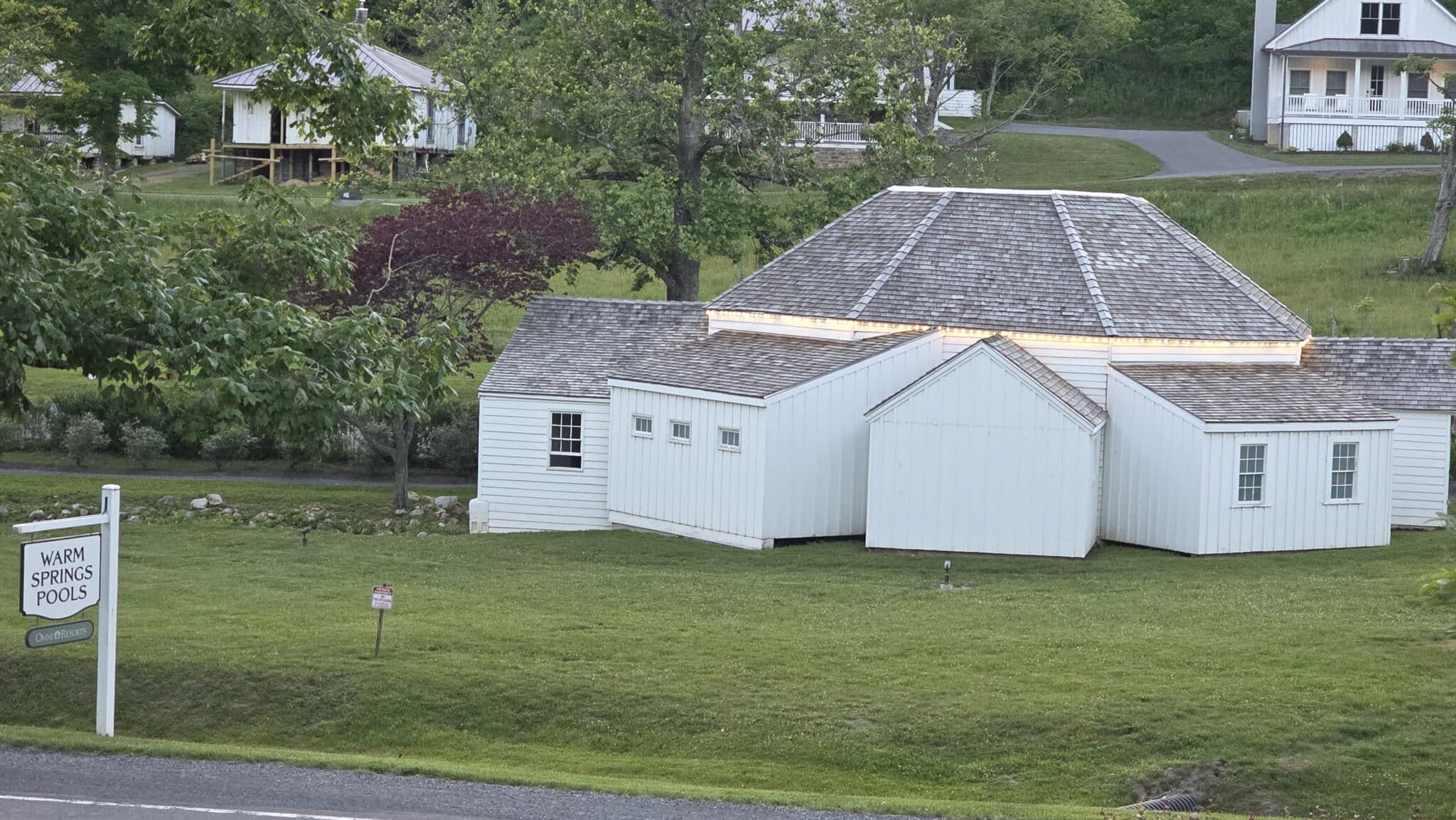 Exterior of the Warm Springs Pools - octagonal white building with green grass and sign.