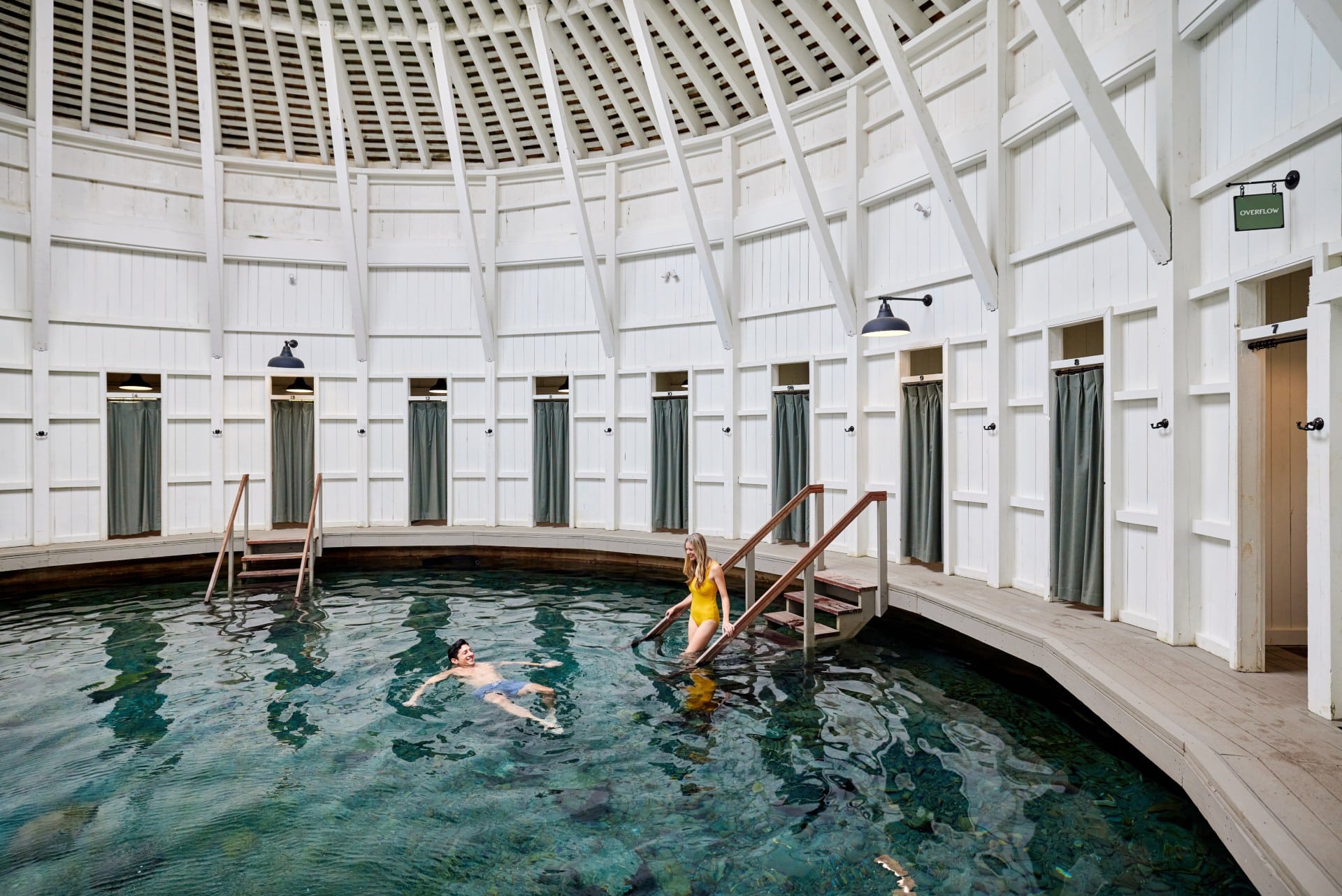 Guests soaking in the naturally warm water inside the historic Warm Springs Pools bathhouse