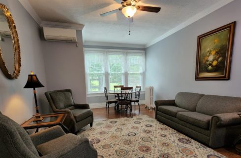 Sitting area with couch, two chairs and round table with four chairs in front of large windows