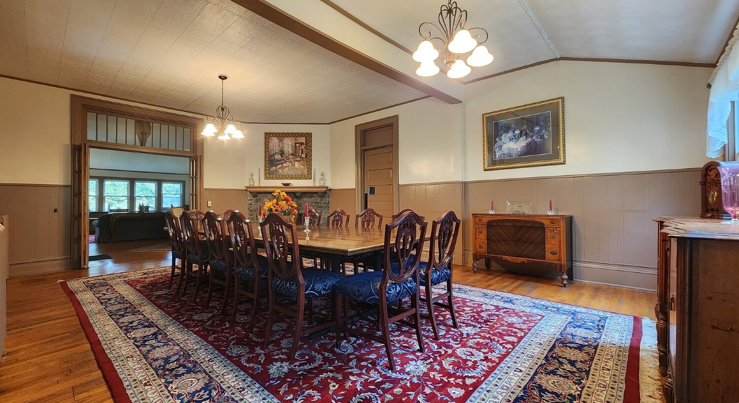 Large dining room with table for twelve, oriental rug, buffet tables, fireplace and doorway into separate living room
