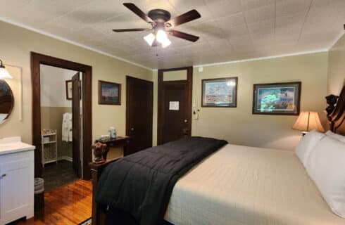 Guest room with king bed, sink vanity in right corner, doorway to private bathroom, and framed artwork on the walls