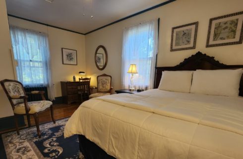 Guest room with queen bed, antique furnishings and windows with lace curtains