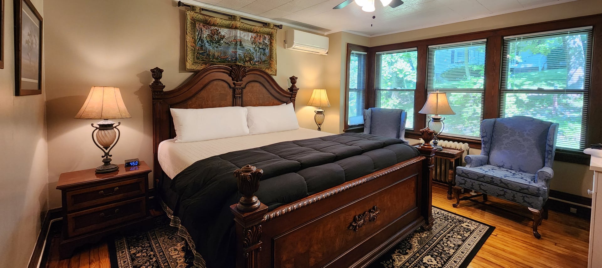 Guest room with king bed, framed artwork and sitting chairs below wall of windows