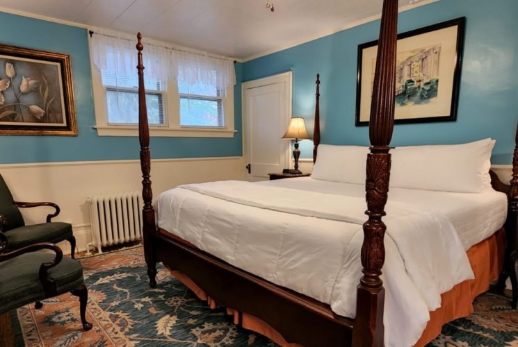 Guest room with four poster bed, side tables with lamps, and two sitting chairs