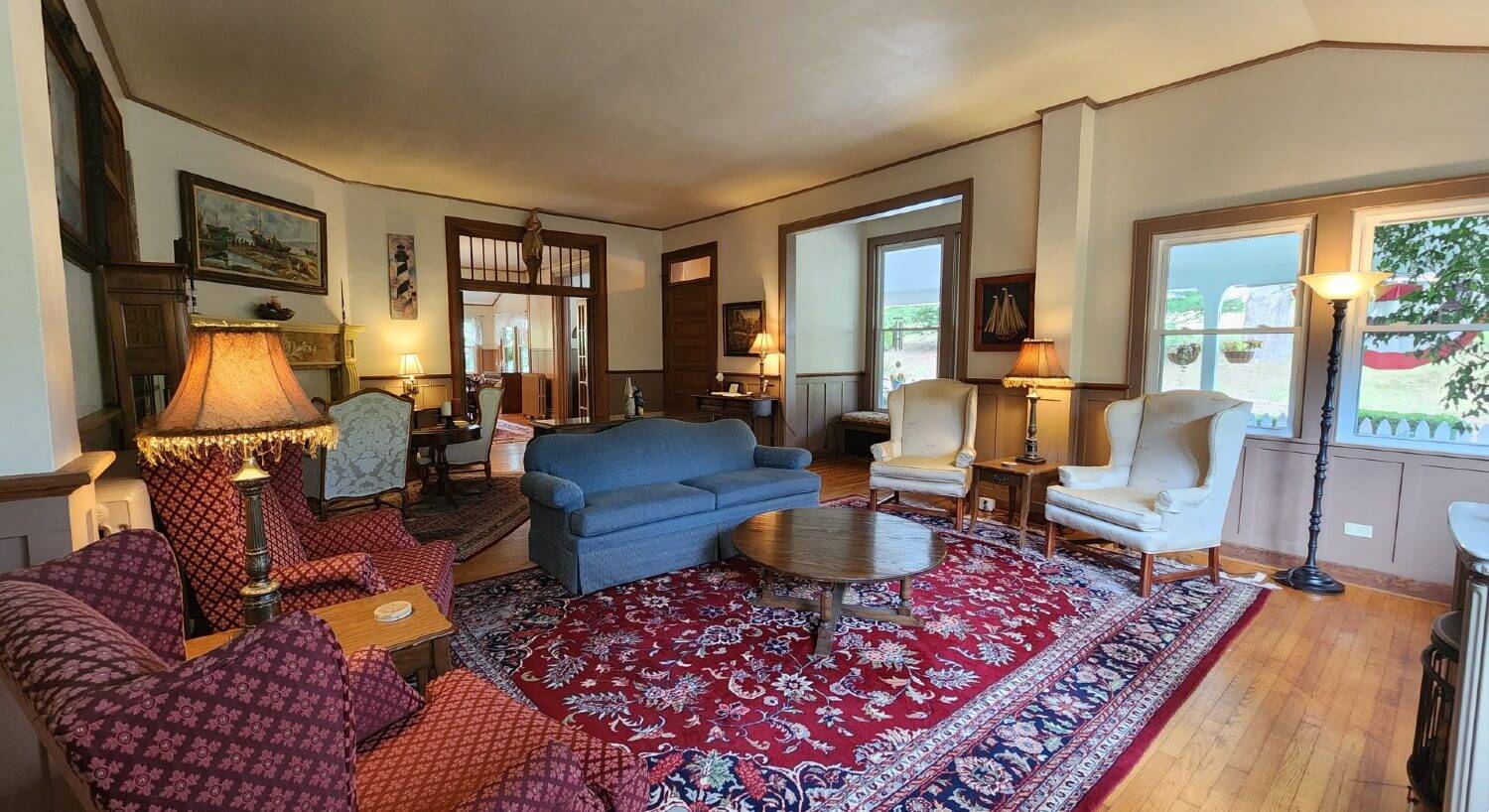 Elegant living room with blue couch, wingback sitting chairs, fireplace and large windows